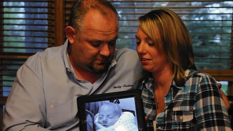 Elizabeth and Phil Peszat hold a photo of their son